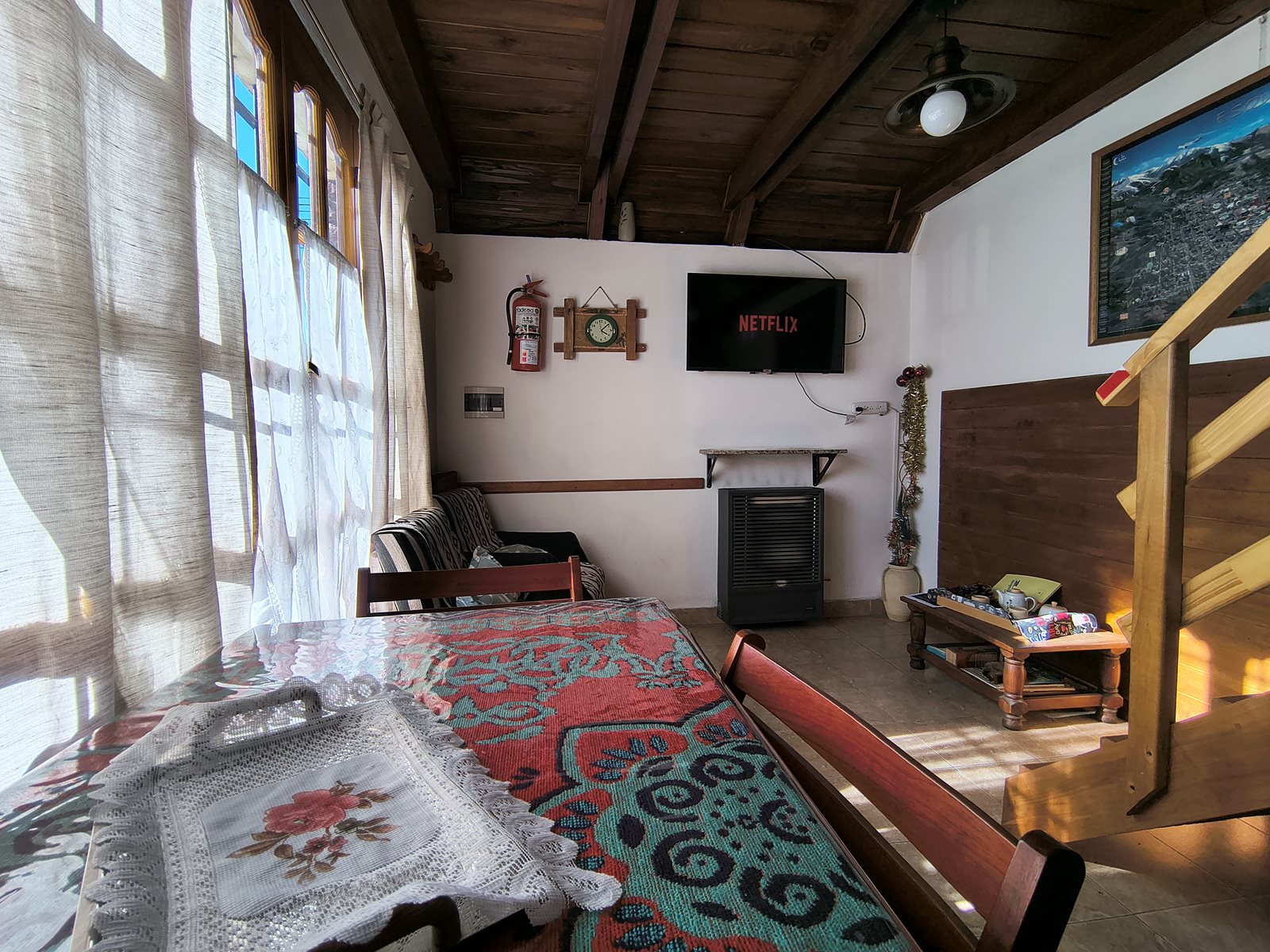Estar y comedor de FREECIS con mesa, televisor, calefactor y escalera de madera
