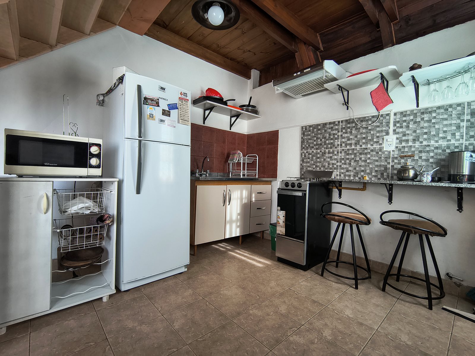 Cocina de FREECIS con heladera, microondas, horno y barra con dos banquetas