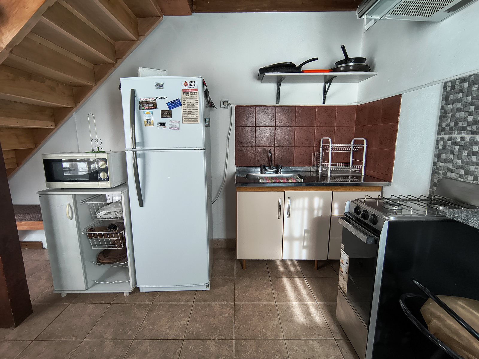 Sector de cocina de FREECIS con pileta, heladera y microondas bajo la escalera