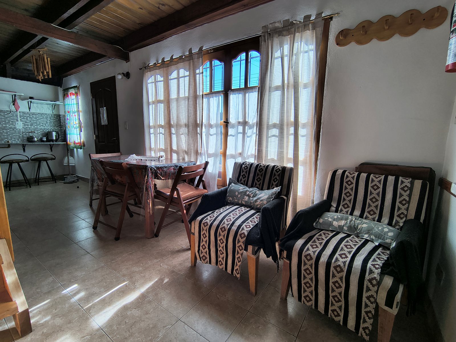 Estar de FREECIS con dos sillones, mesa de comedor y ventanas con cortinas