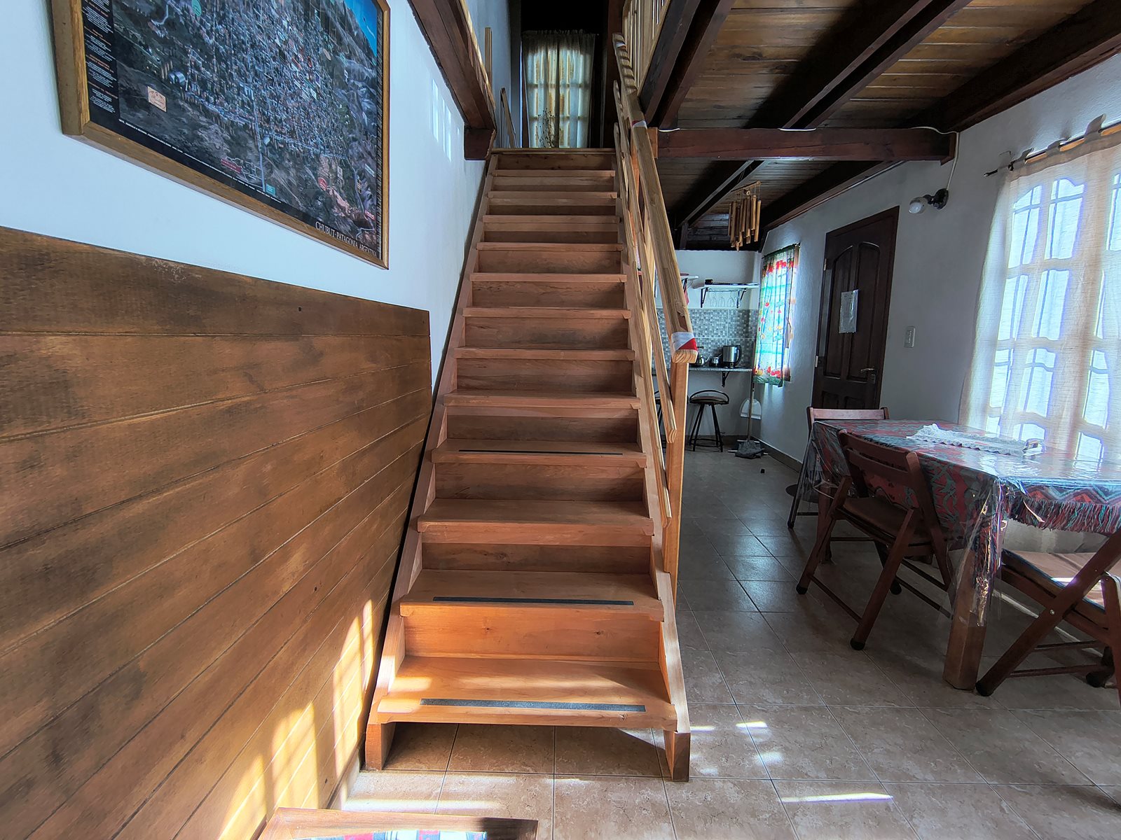 Escalera de madera de FREECIS junto al comedor, con cocina al fondo