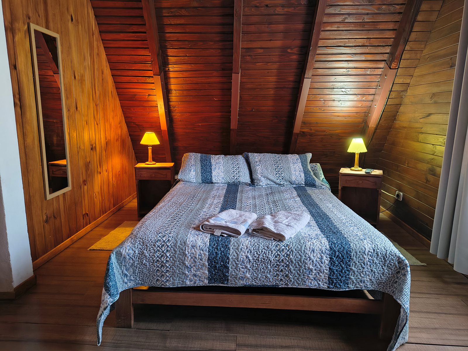 Cama doble de FREECIS con cubrecama azul, toallas dobladas y lámparas de mesa